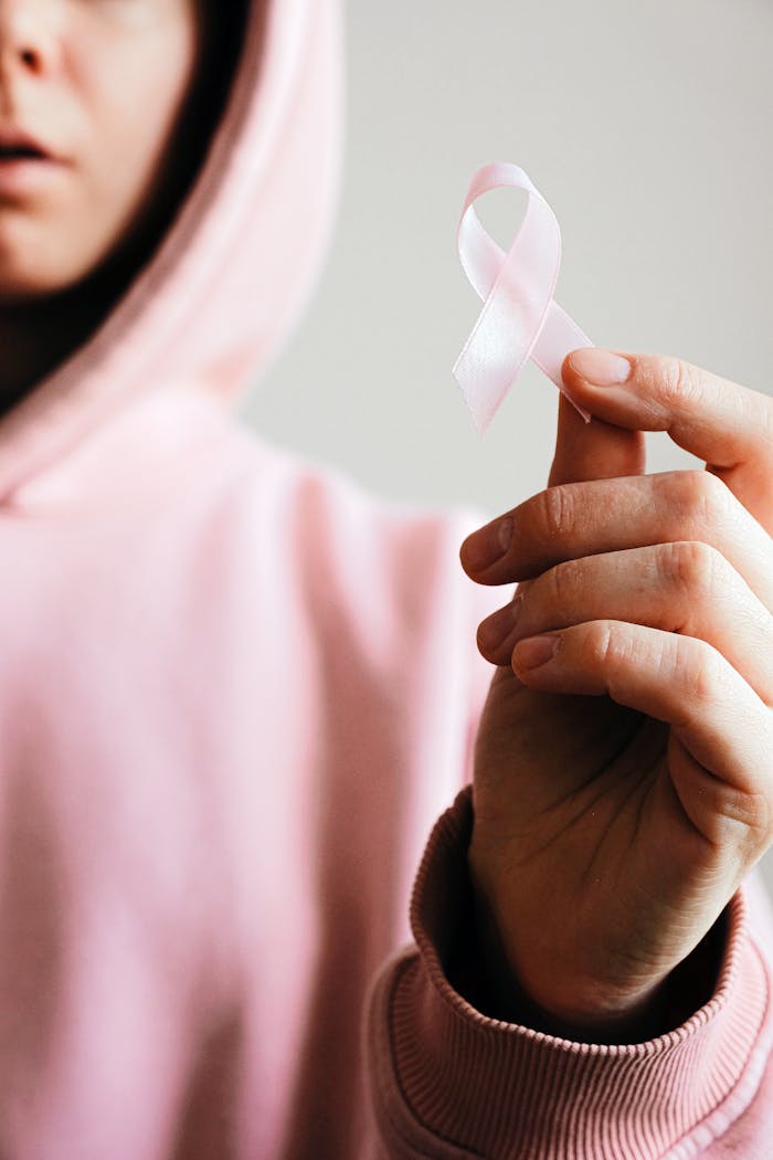 about-us Close-up of a person holding a pink ribbon symbolizing breast cancer awareness.